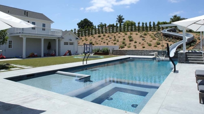 Side angle view of pool with a waterslide built in Photo