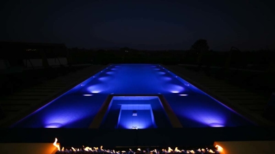 Sleek outdoor aquatic space enhanced with illuminated touches and flaming features. Photo