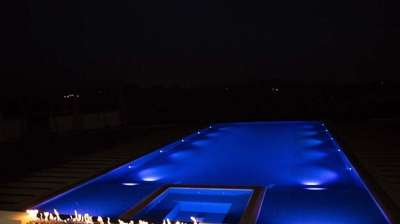 Trendy outdoor pool equipped with dynamic lighting and fiery additions. Photo