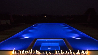 Contemporary swimming area with illuminated accents and fiery embellishments. Photo