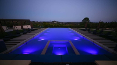 A refined oasis complete with patio seating and a grand pool at dusk. Photo