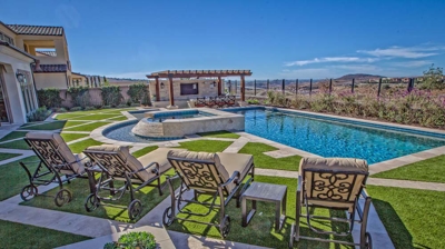 Pool chairs within lounging area alongside a gorgeous pool Photo