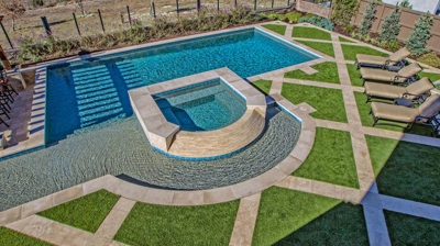 Curved jacuzzi and pool design with green grass landscaping Photo