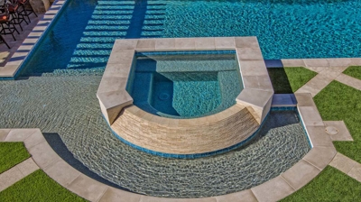 Curved jacuzzi and pool design with green grass landscaping Photo