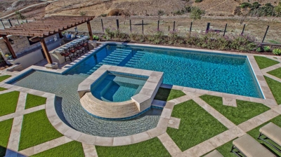 Curved jacuzzi and pool design with green grass landscaping Photo