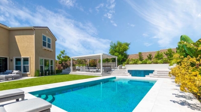 Rectangular pool and oval jacuzzi with lounging chairs on a sunny day Photo