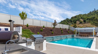 Patio section of backyard with outdoor grill station and pool Photo