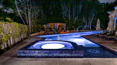 Lit up pool with jacuzzi in the night setting Photo