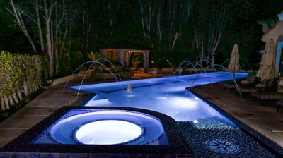Lit up pool with jacuzzi in the night setting Photo