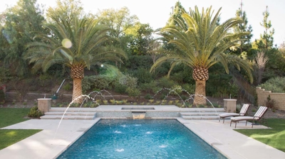 Modern backyard pool with water features and attached spa Photo