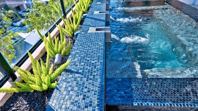 Urban rooftop haven boasting a spa alongside a crackling fire pit and verdant potted greenery. Photo