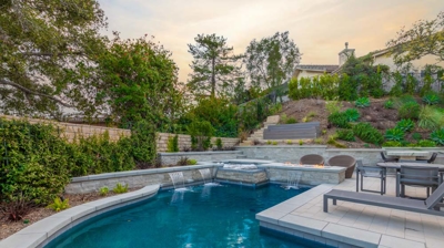 Backyard pool with water fountain features and attached spa Photo