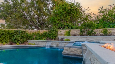 Backyard pool with water features and fire pit Photo