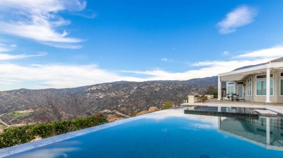 Infinity edge modern pool design and view of house Photo