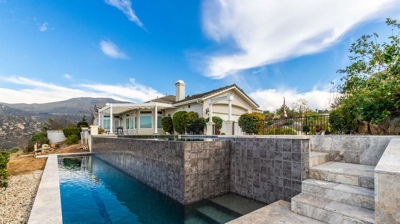 Infinity edge modern pool design and view of house detail Photo