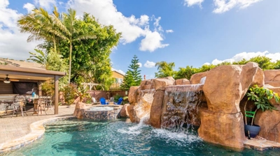 A blissful scene of a curved pool, hot tub, and soothing waterfall Photo