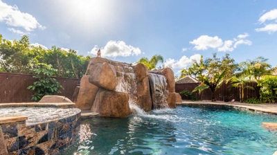 Relaxation awaits: a curved pool adorned with a hot tub and cascading waterfall Photo