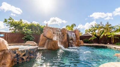 Elegant curved pool with a hot tub and picturesque waterfall feature Photo