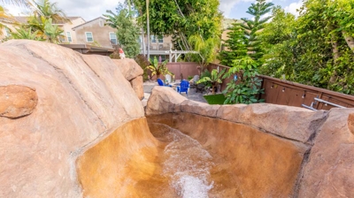Curved pool and hot tub surrounded by nature's beauty and a tranquil waterfall Photo