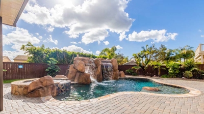 A blissful scene of a curved pool, hot tub, and soothing waterfall Photo