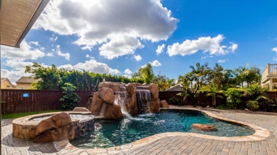 Relaxation awaits: a curved pool adorned with a hot tub and cascading waterfall Photo