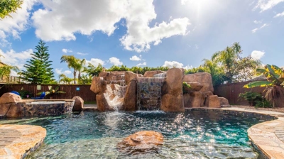 Elegant curved pool with a hot tub and picturesque waterfall feature Photo