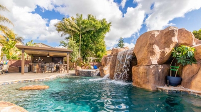 Sunny day at the poolside: curved pool, hot tub, and enchanting waterfall Photo