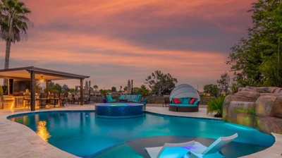Mesmerizing view of the oval pool and hot tub illuminated in the evening Photo