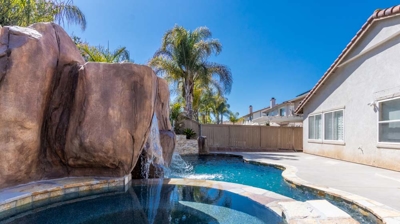 Pool and hot tub surrounded by lush greenery, with a captivating waterfall as the centerpiece Photo