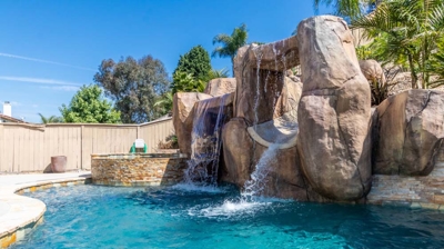 A dreamy landscape featuring a pool, hot tub, and cascading waterfall Photo