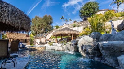 Shaded pool and hot tub nestled beneath a cascading waterfall Photo