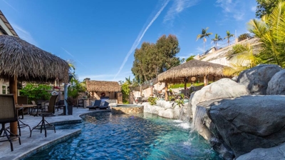 A serene retreat featuring a shaded pool and hot tub with a scenic waterfall Photo