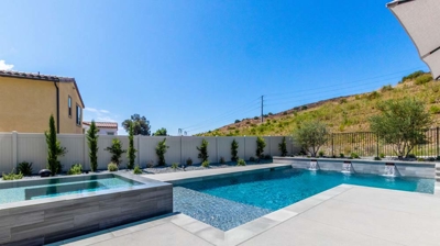 Rectangular pool nestled in a lush suburban backyard, backed by rolling hills Photo