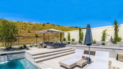 "Scenic view of a rectangular pool in a suburban backyard with hills in the background Photo