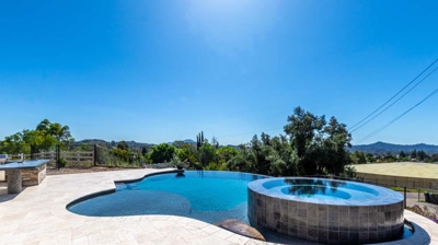 Sunny day at the poolside with a curved pool and elevated hot tub Photo
