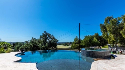 Glistening curved pool and raised hot tub under the radiant sun Photo