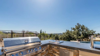 Well-appointed outdoor kitchen featuring a grill, oven, and taps for seamless outdoor cooking Photo