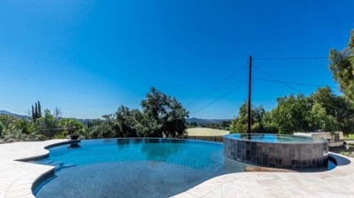 Curved pool and raised hot tub basking in sunlight on a beautiful day Photo