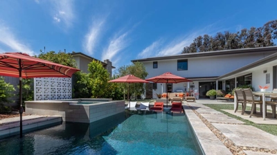 Sunny suburban backyard featuring a rectangular pool and hot tub Photo