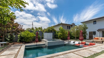 Sunny suburban retreat with a rectangular pool and hot tub as the focal point Photo