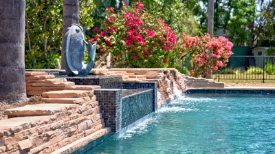 Side view of a rocky pool wall with waterfall Photo