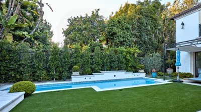 A large section of green grass before a built in pool Photo