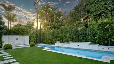 A long rectangular pool in the backyard with cement pavers Photo