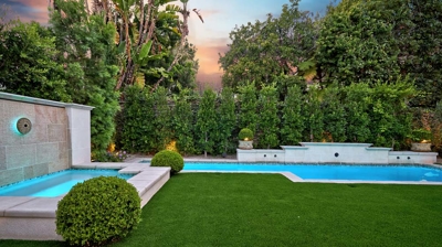 A jacuzzi next to a pool with cement pavers in front Photo