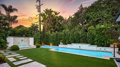 A sunset view of a backyard with a pool and jacuzzi Photo