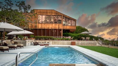 A pool with built in jacuzzi next to a large home Photo