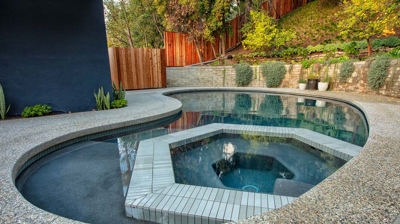 View of curvy pool with built in geometric shaped jacuzzi Photo