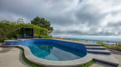 Big steps leading up to a pool and jacuzzi with a view of the ocean Photo