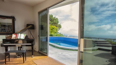 View of the backyard pool from inside a house with large slider doors Photo