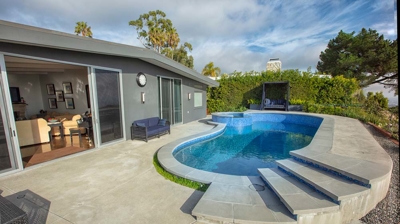 Backyard pool next to a home with the back double slider open Photo
